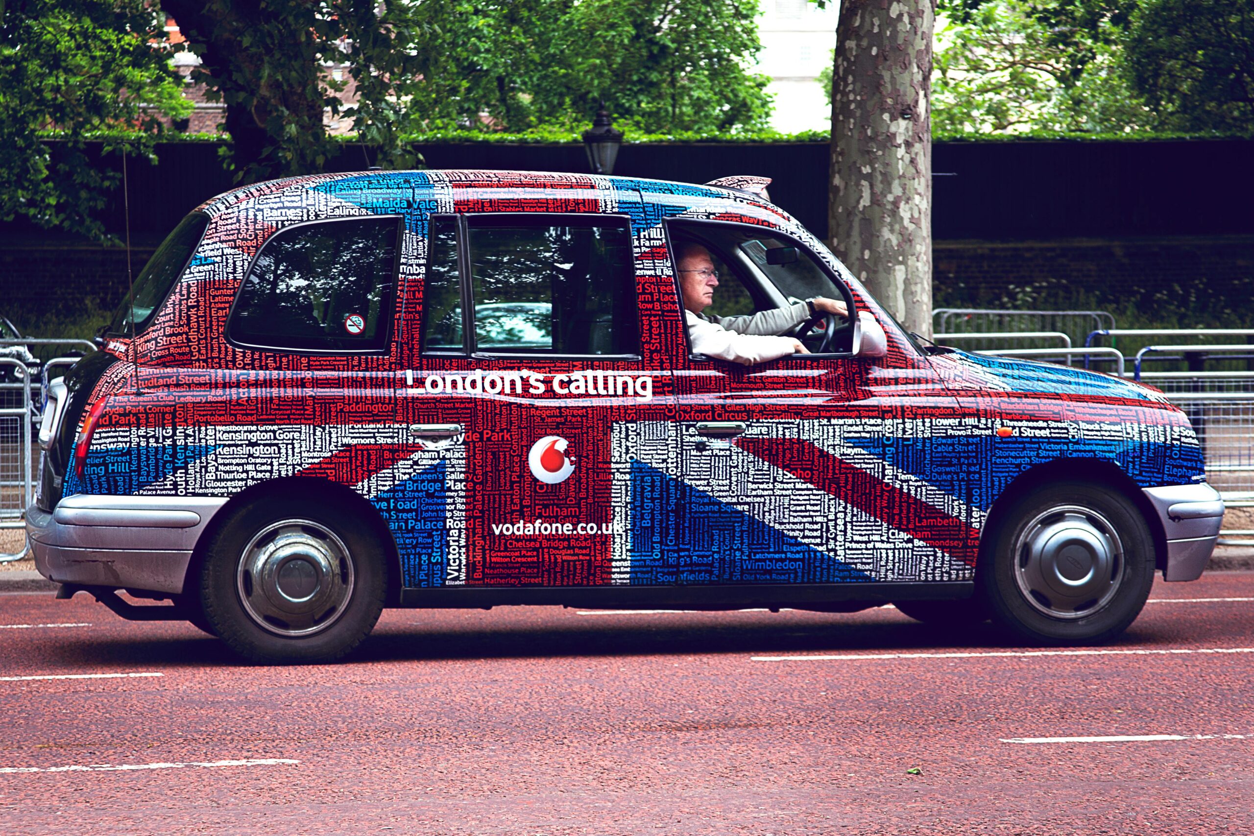 A vibrant Union Jack styled London taxi driving through central London.