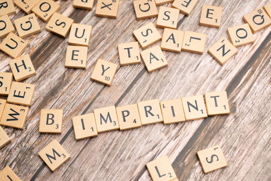 Wooden Scrabble tiles arranged on a wooden surface, spelling 'Imprint'.